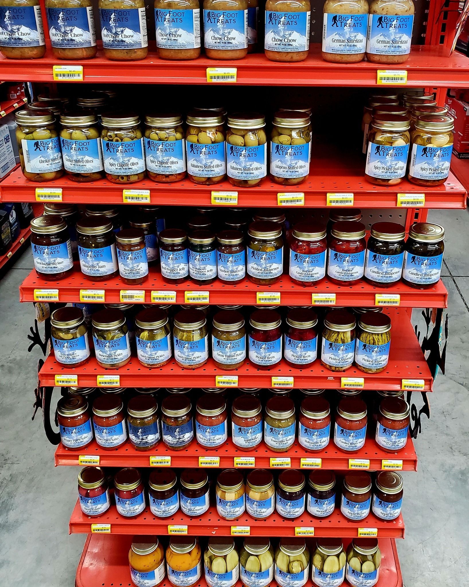 Rows of glass jars with blue labels arranged neatly on red shelves in a store aisle.