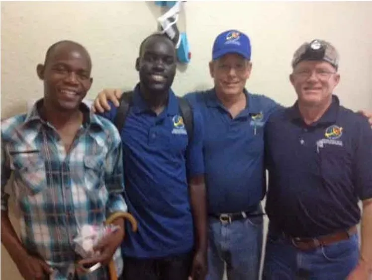 Four men smiling, posing. Two in blue shirts, two in plaid and navy shirts.