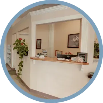 Reception desk in a cream-colored office with framed artwork and plants.