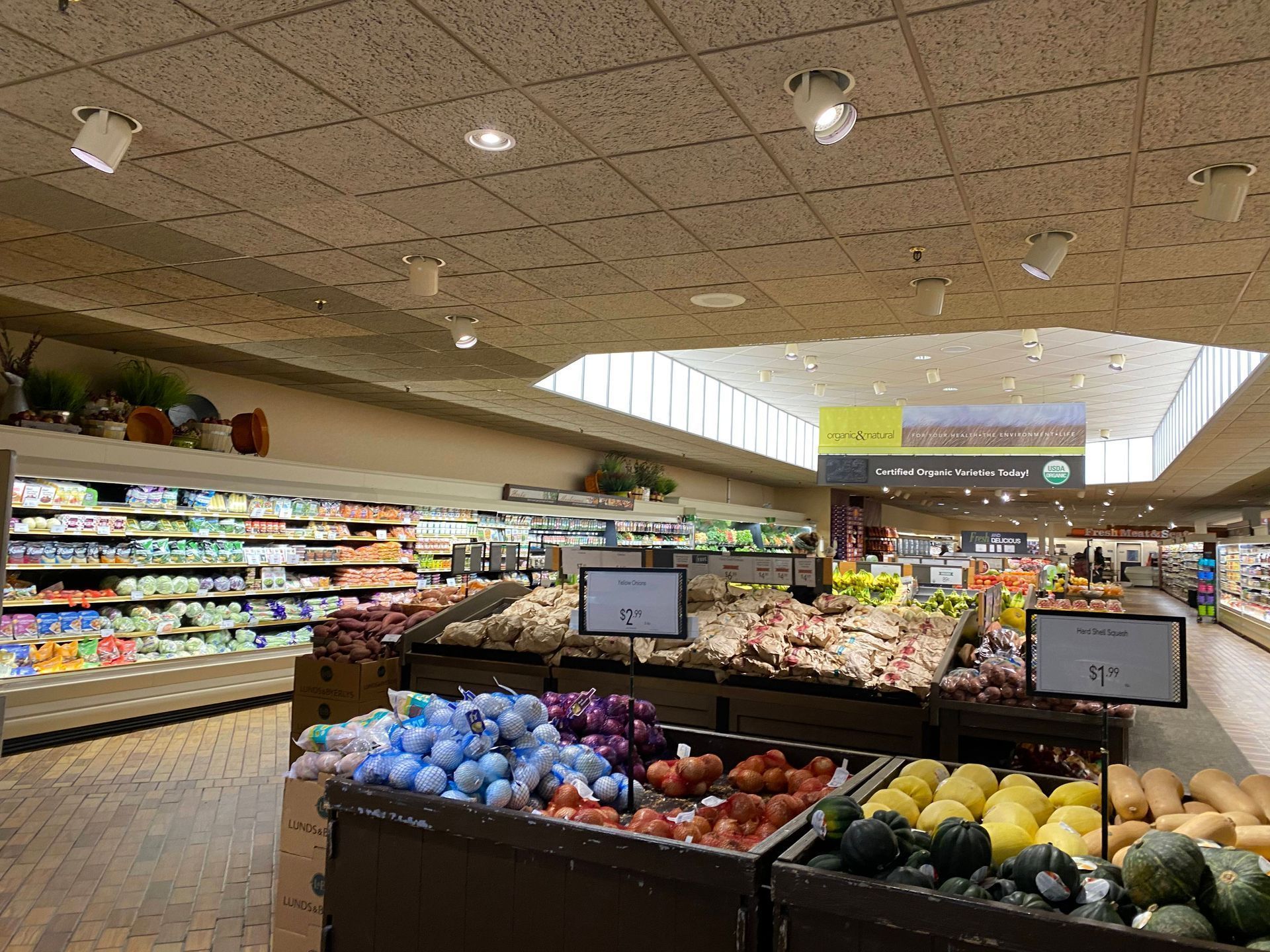 Produce aisle in a grocery store, with various fruits and vegetables displayed.