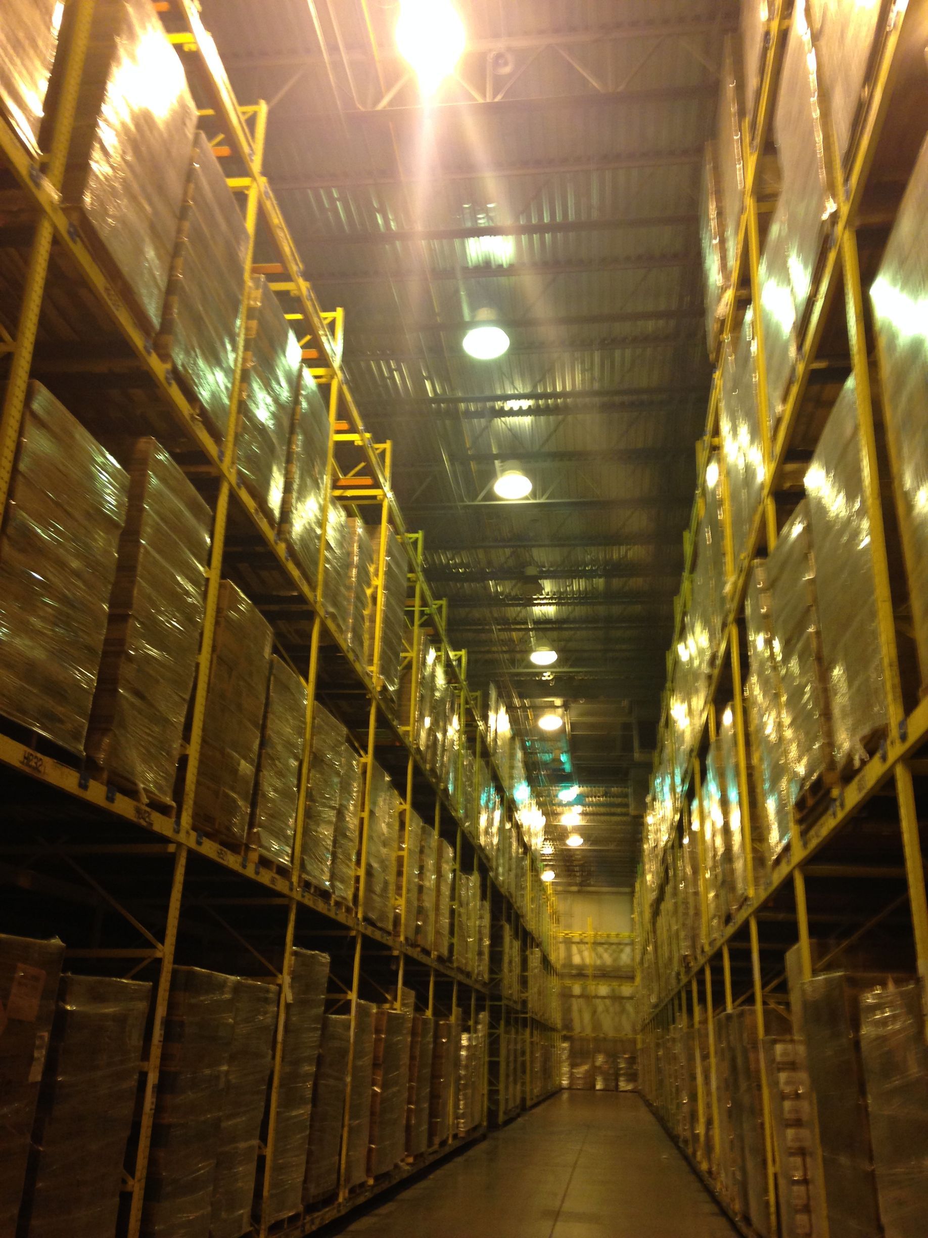 Rows of packaged goods stored on yellow warehouse shelving.
