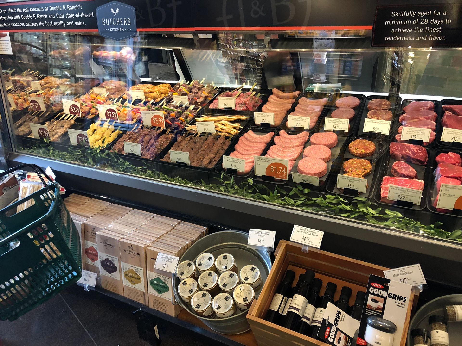Meat display case at a grocery store, with various cuts of meat and prepared foods on display.