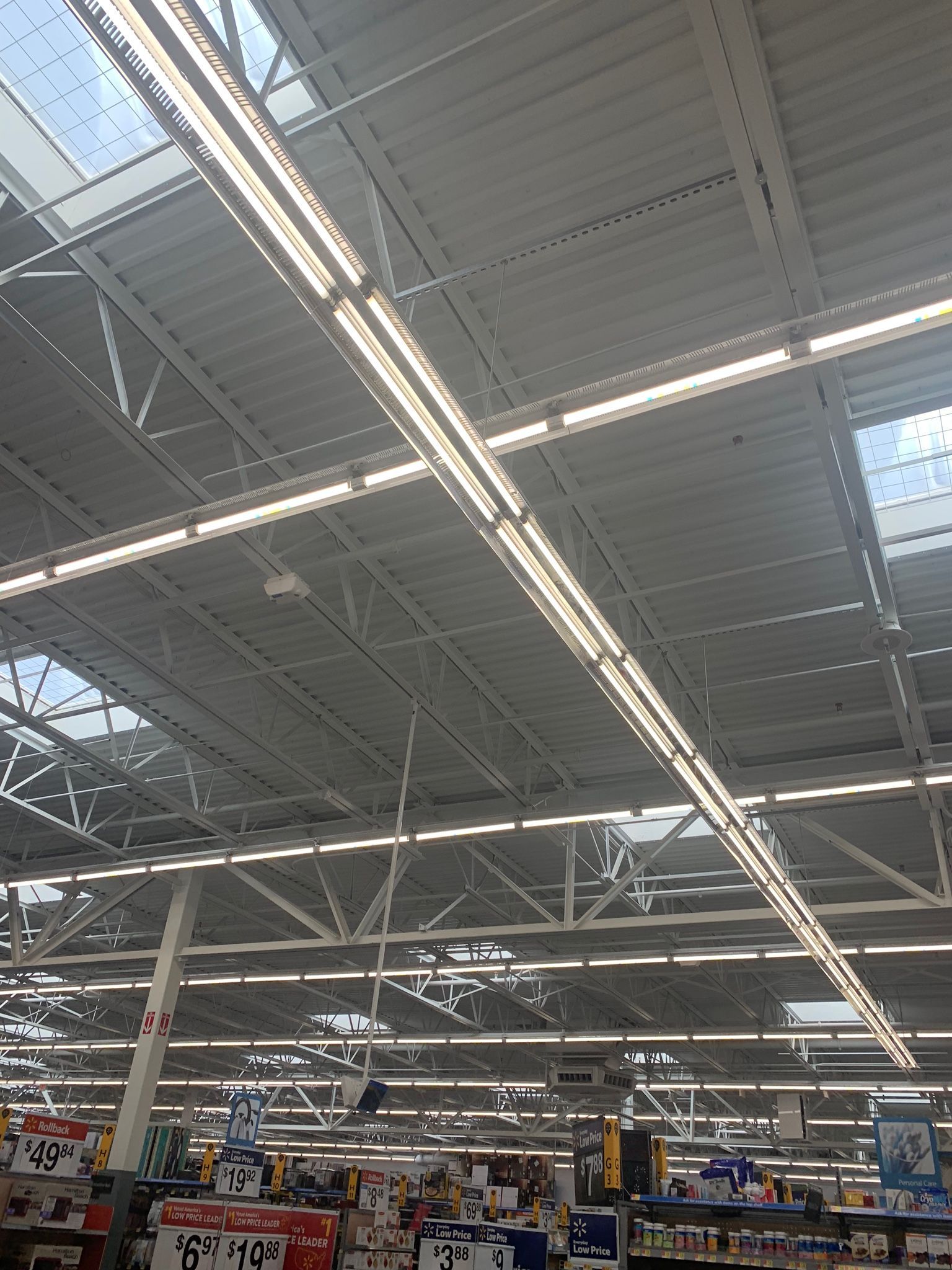 Ceiling of a large store with skylights, fluorescent lights, and metal beams.