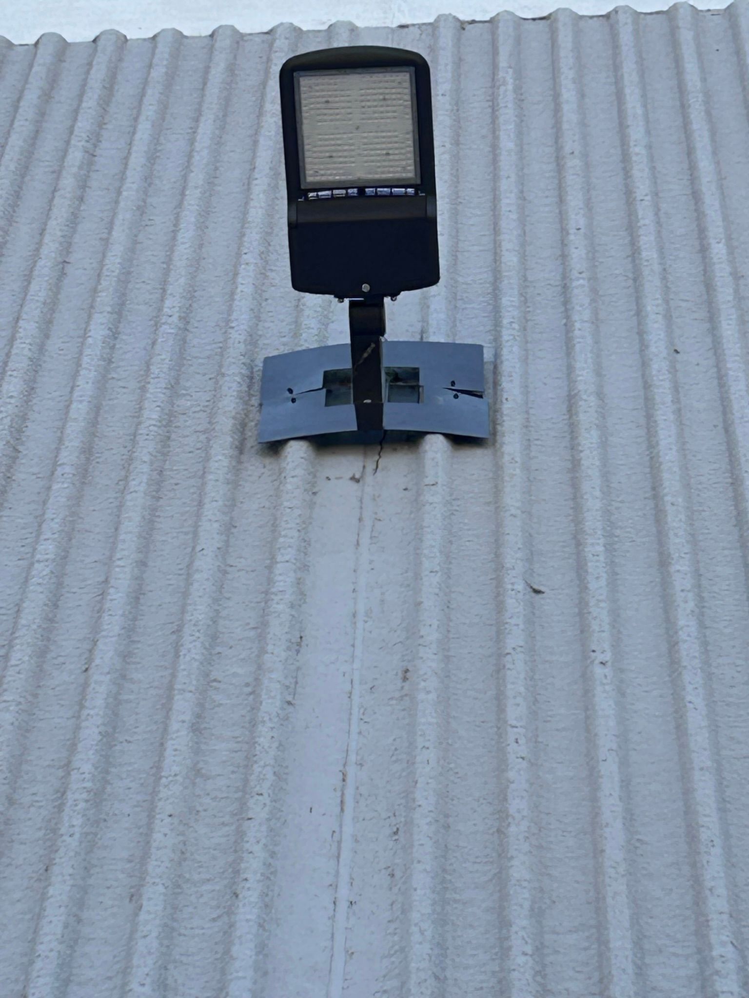 LED floodlight mounted on a corrugated metal wall.