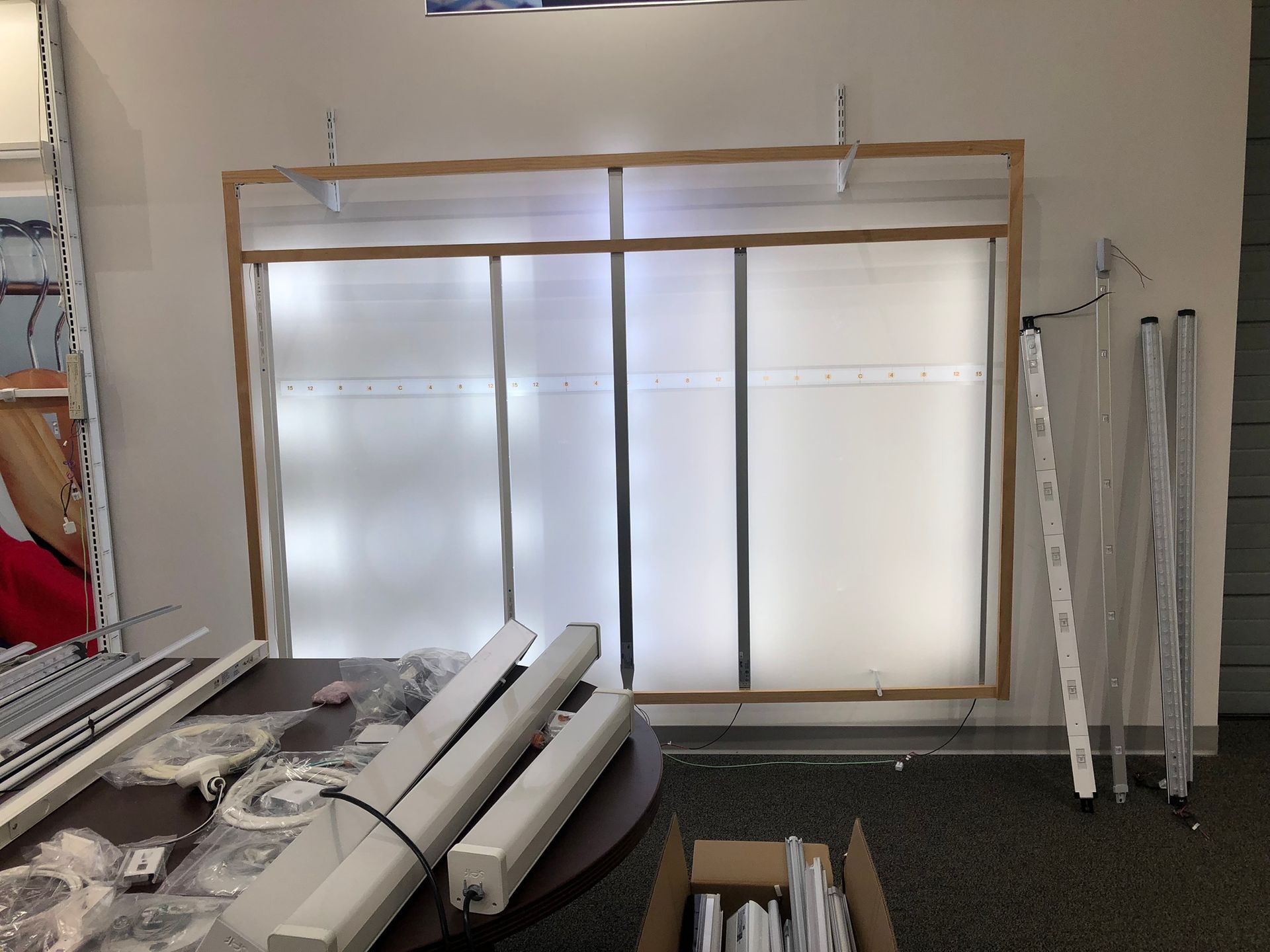 A lit display case with white panels and a wooden frame, and several disassembled light fixtures.
