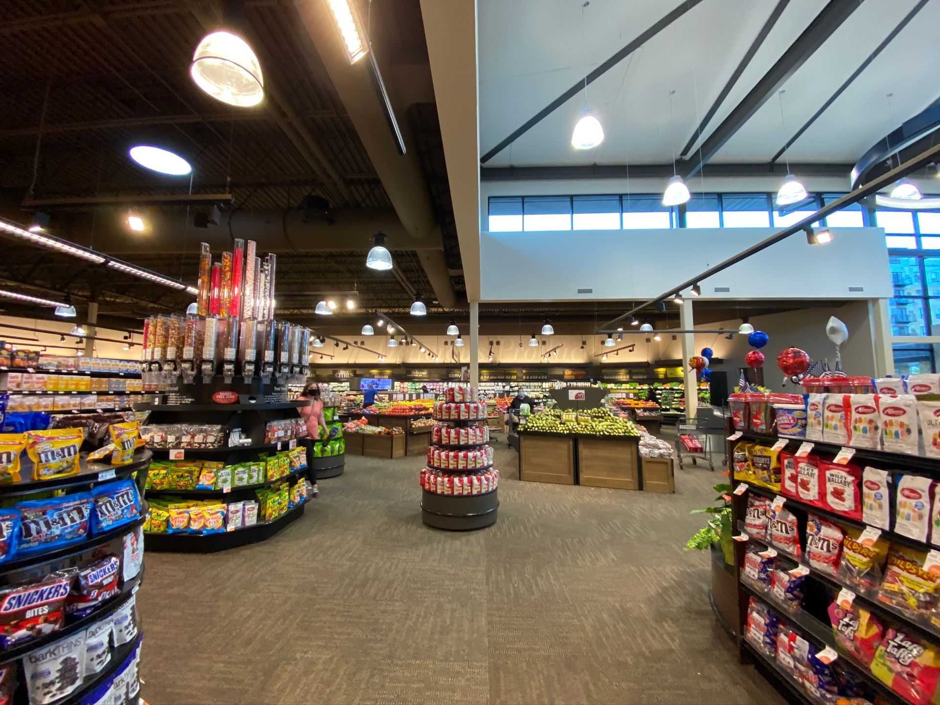 Interior view of a grocery store aisle with shelves of snacks and produce.