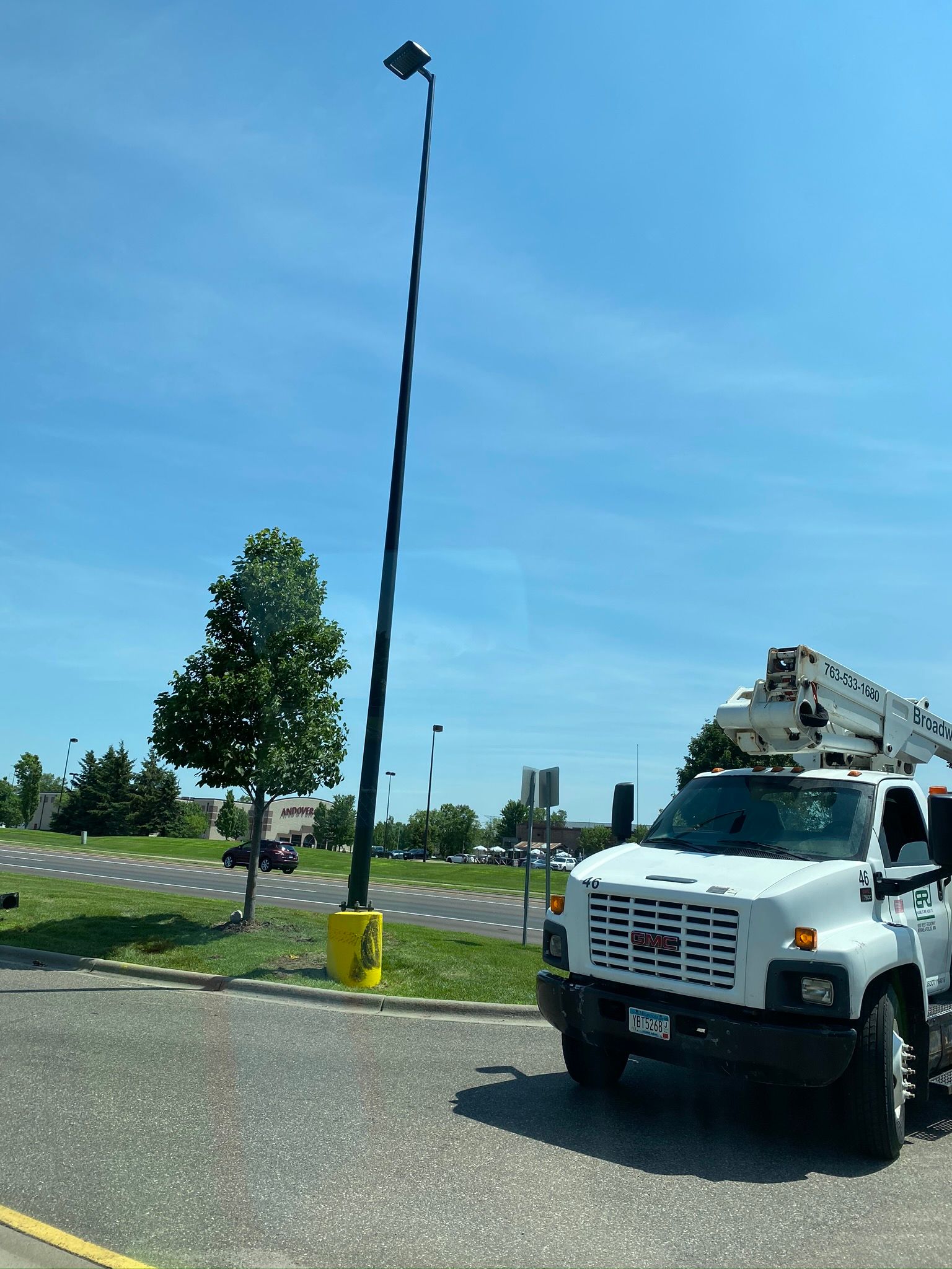 Utility truck near a tall street light post against a blue sky.