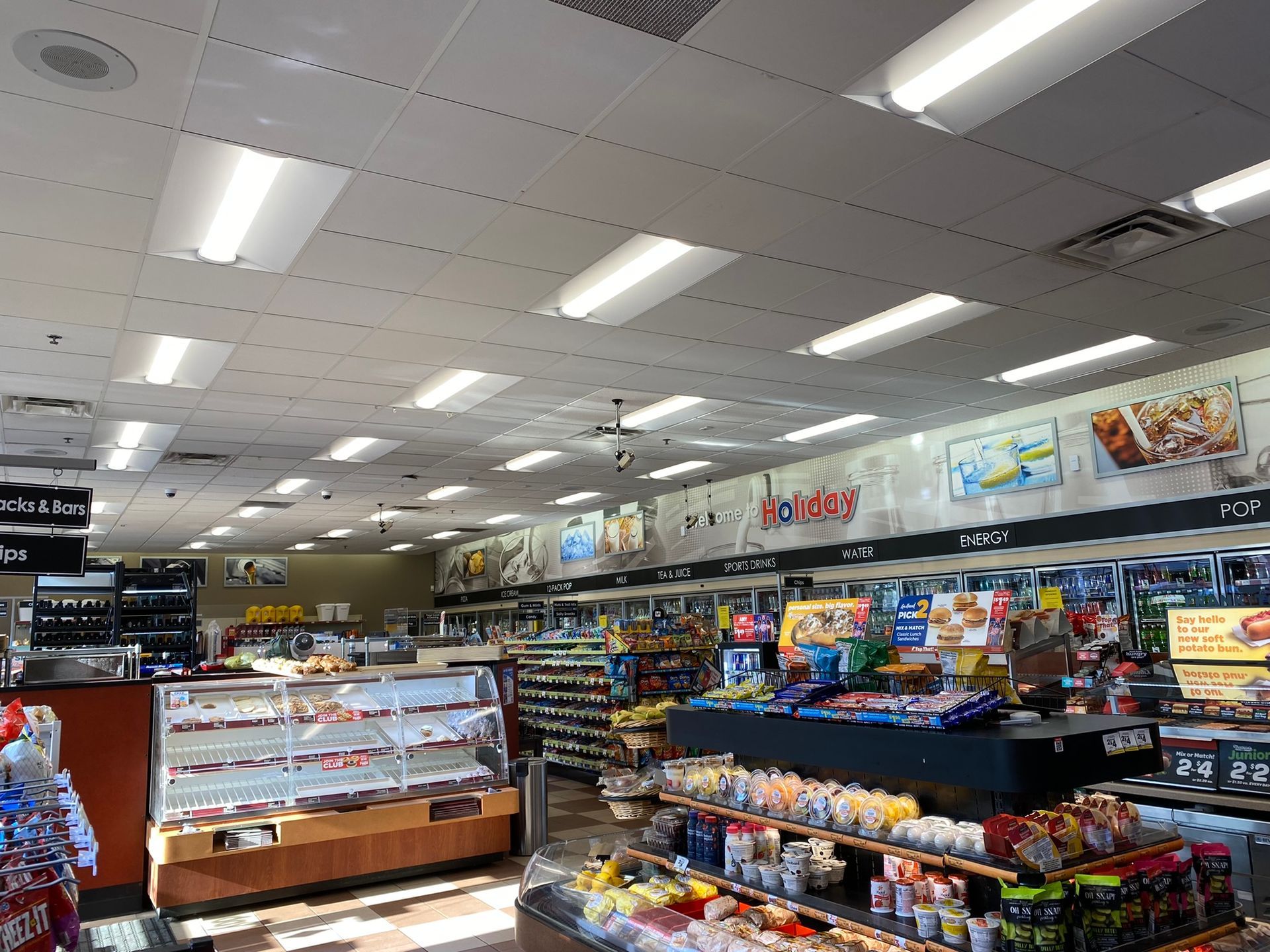 Interior of a convenience store with shelves of products, including snacks and drinks, under fluorescent lights.