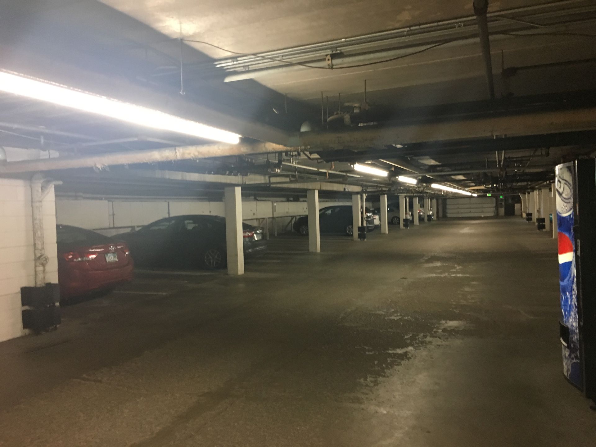 Indoor parking garage with parked cars and overhead lighting.