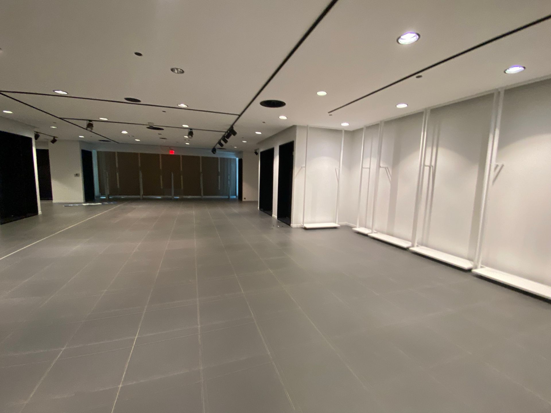 Empty, modern retail space with gray tiled floor, white walls, and track lighting.