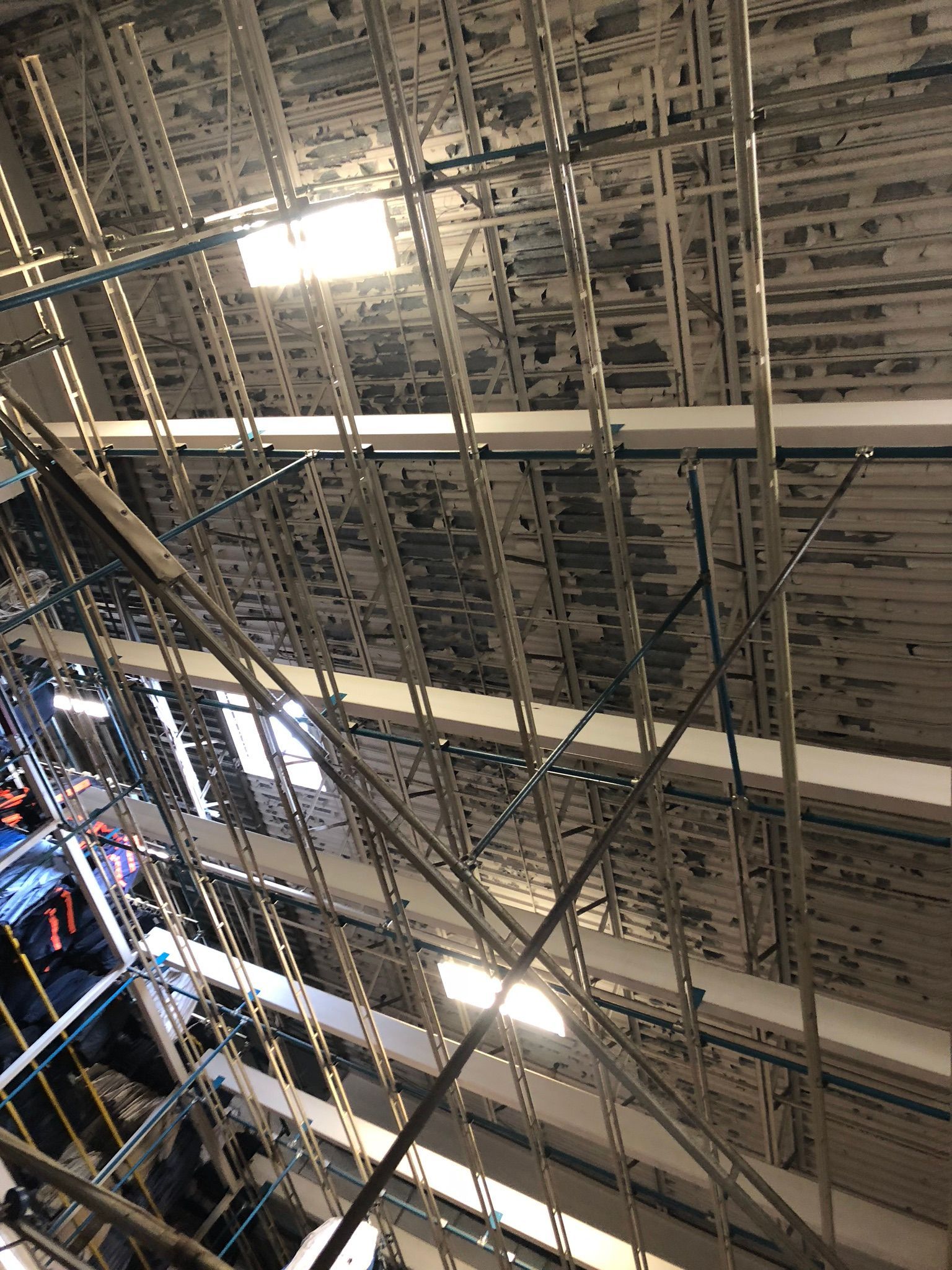 Metal framework and ceiling, with lights visible. Dark clothing hangs below.
