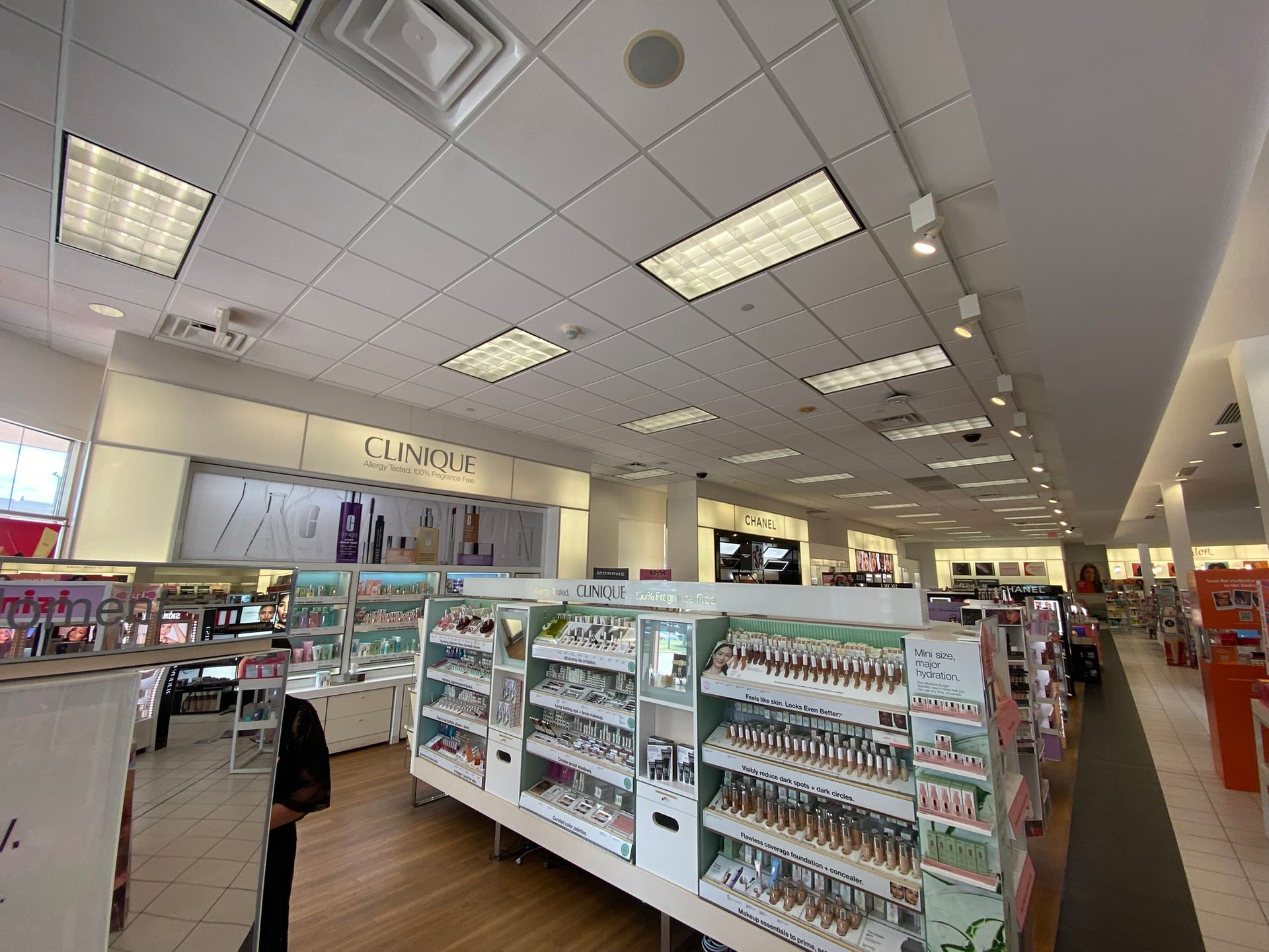 Cosmetics store interior with shelves of products and fluorescent lighting. Clinique display visible.