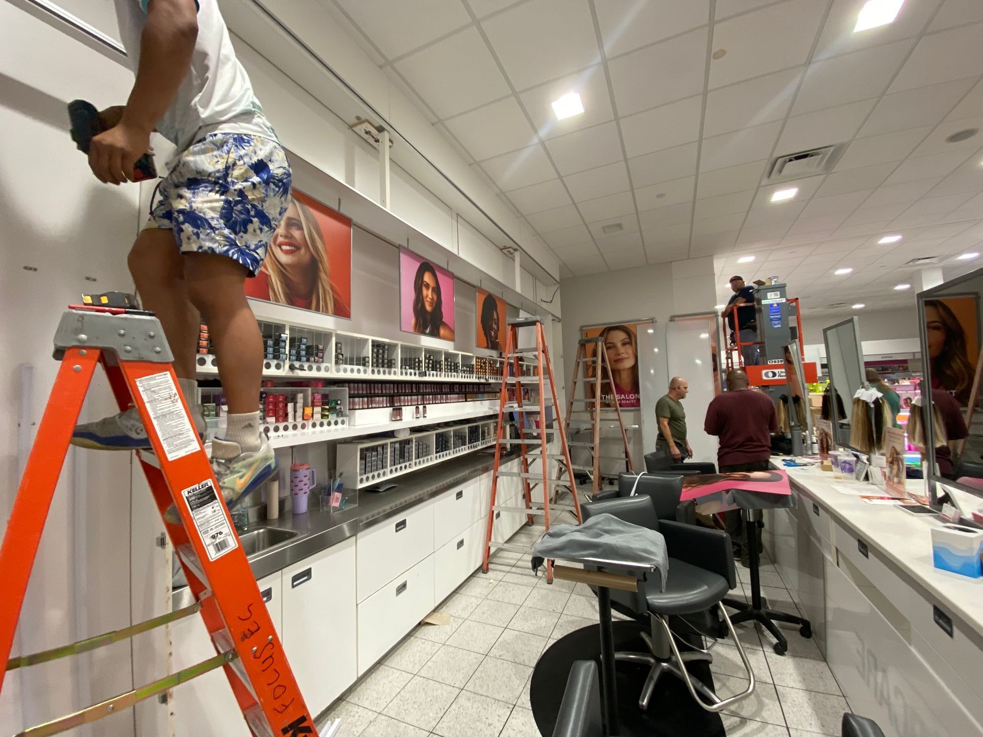 People working in a beauty store, setting up shelves and displays.
