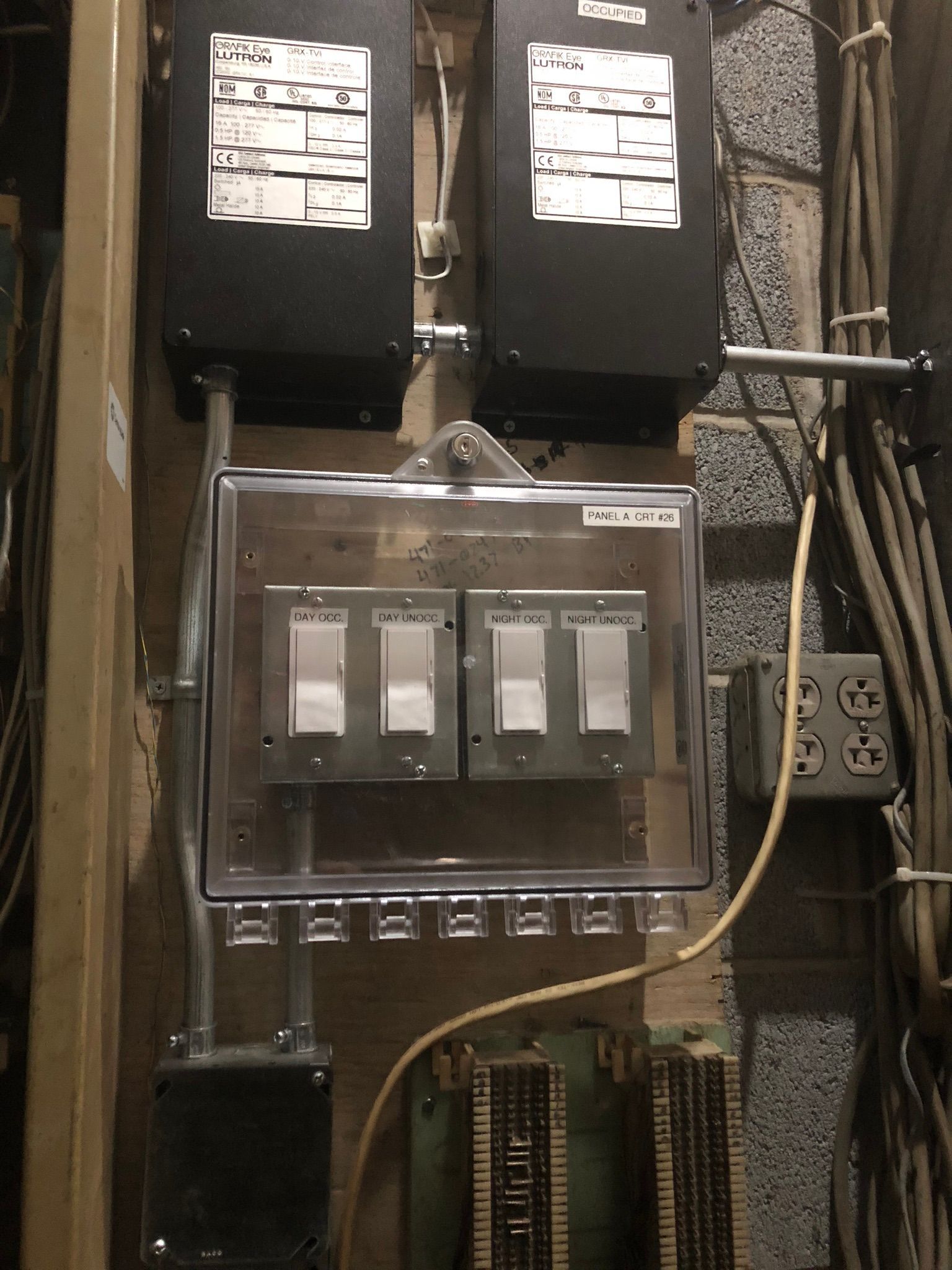 Electrical control panel with switches, wiring, and boxes mounted on a wall.