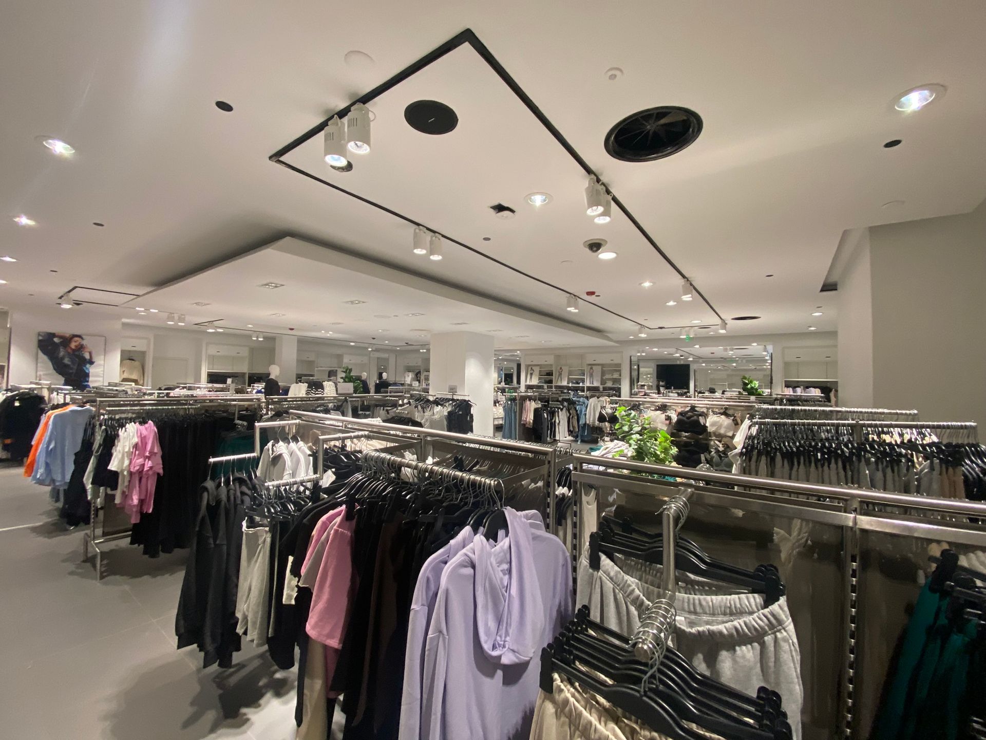 Clothing store interior with clothing racks and overhead track lighting.