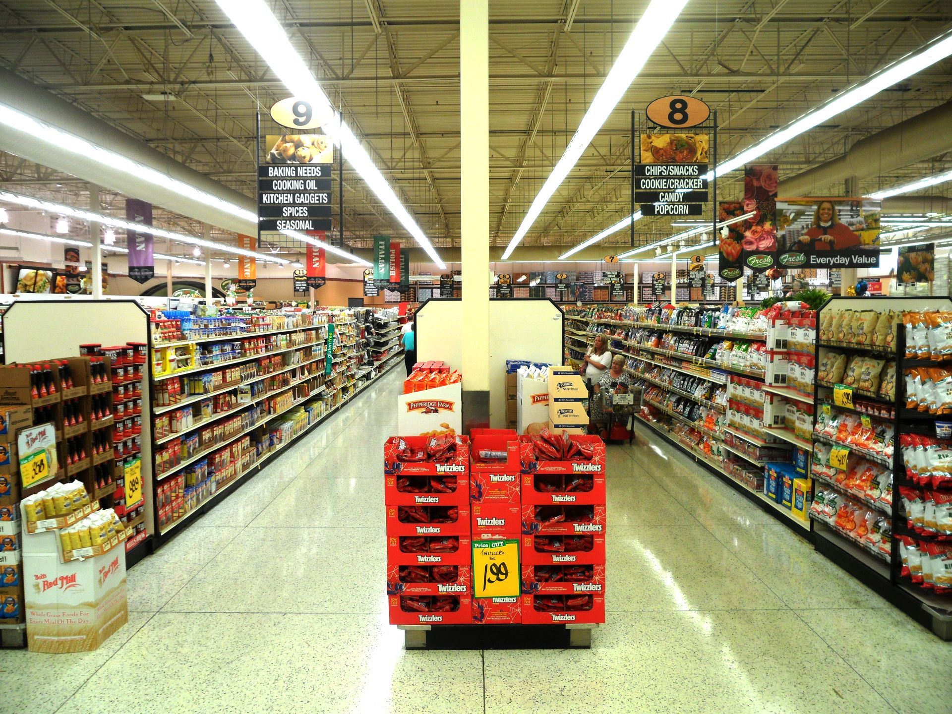 Grocery store aisle with products on shelves and center display.