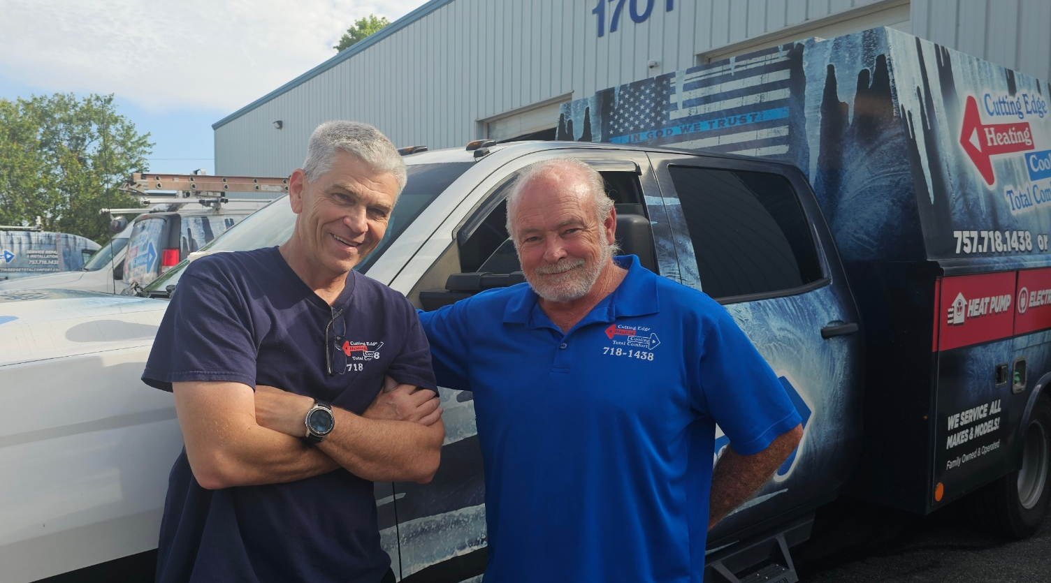 Two men smiling beside a branded service van outside a building