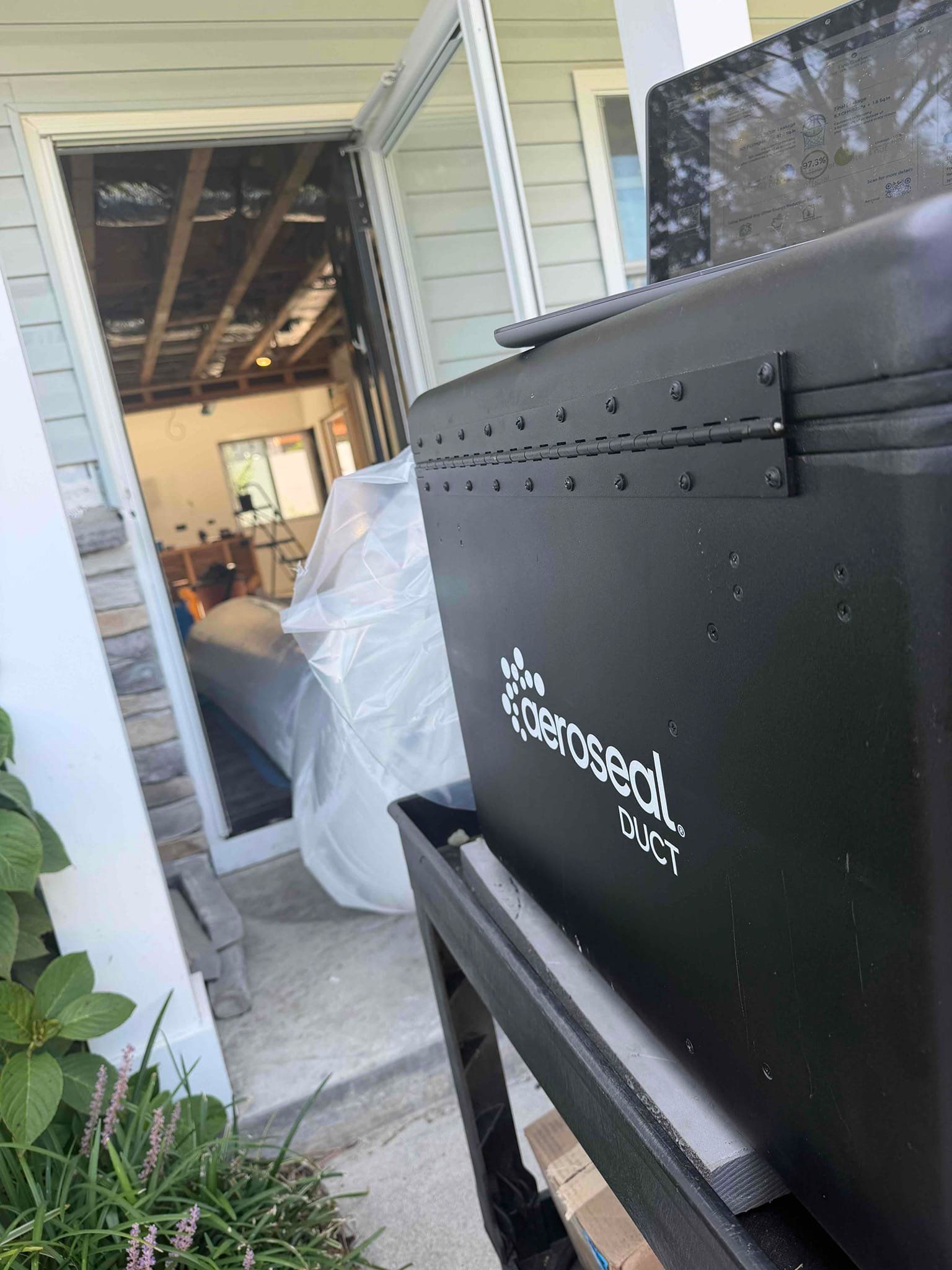Black grill by a doorway beside a plastic-covered item inside a home garage