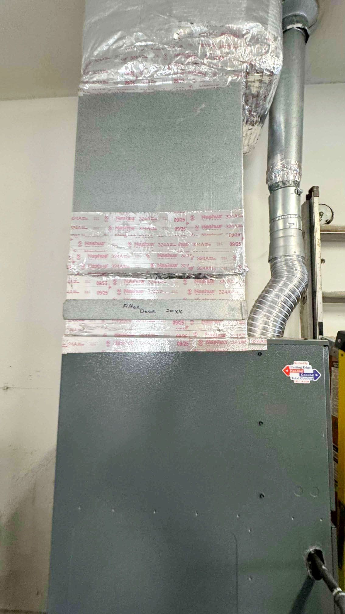 Gray HVAC ductwork with insulated vents and foil tape above a dark cabinet in a utility room.
