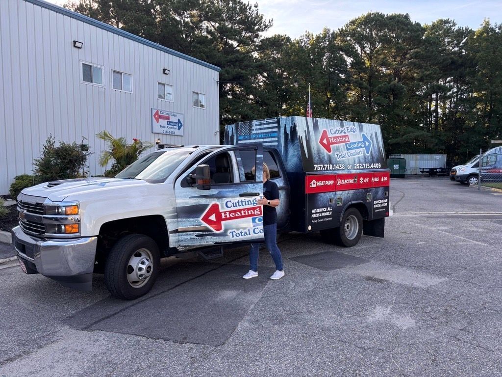 White box truck with red signage parked outside a building, with a person standing by the driver’s door