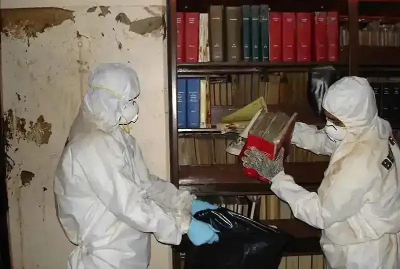 two people in protective suits are working in a library