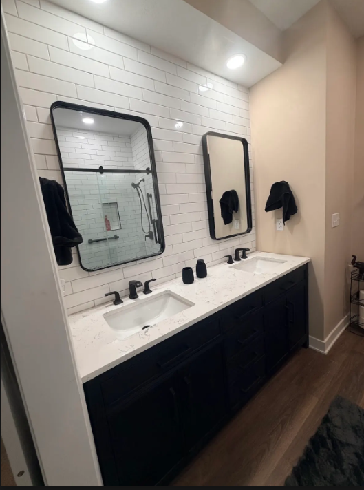 Modern bathroom vanity with double sinks, black-framed mirrors, and white subway tile backsplash.