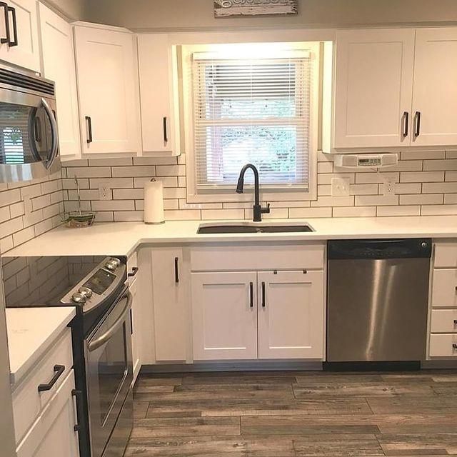 Modern kitchen with white cabinets, subway tile backsplash, black fixtures, and stainless steel appliances