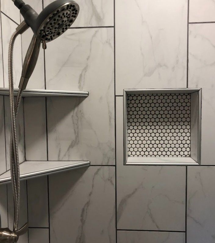 Shower with handheld showerhead, built-in corner shelves, and hex tile wall niche