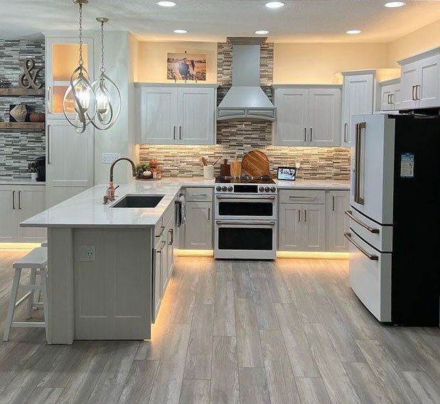 Modern white kitchen with gray island, stainless appliances, and under-cabinet lighting