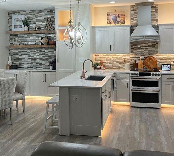Bright modern kitchen with gray cabinets, island, pendant lights, and stainless steel appliances