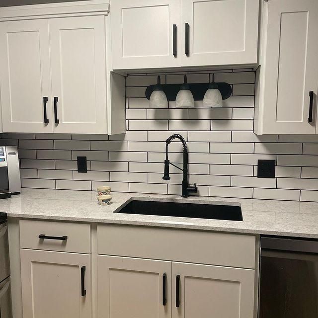 Modern white kitchen with black fixtures, subway tile backsplash, and a black sink and faucet