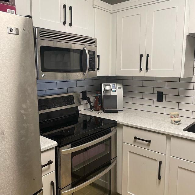 Modern kitchen with stainless steel appliances, white cabinets, and black countertops