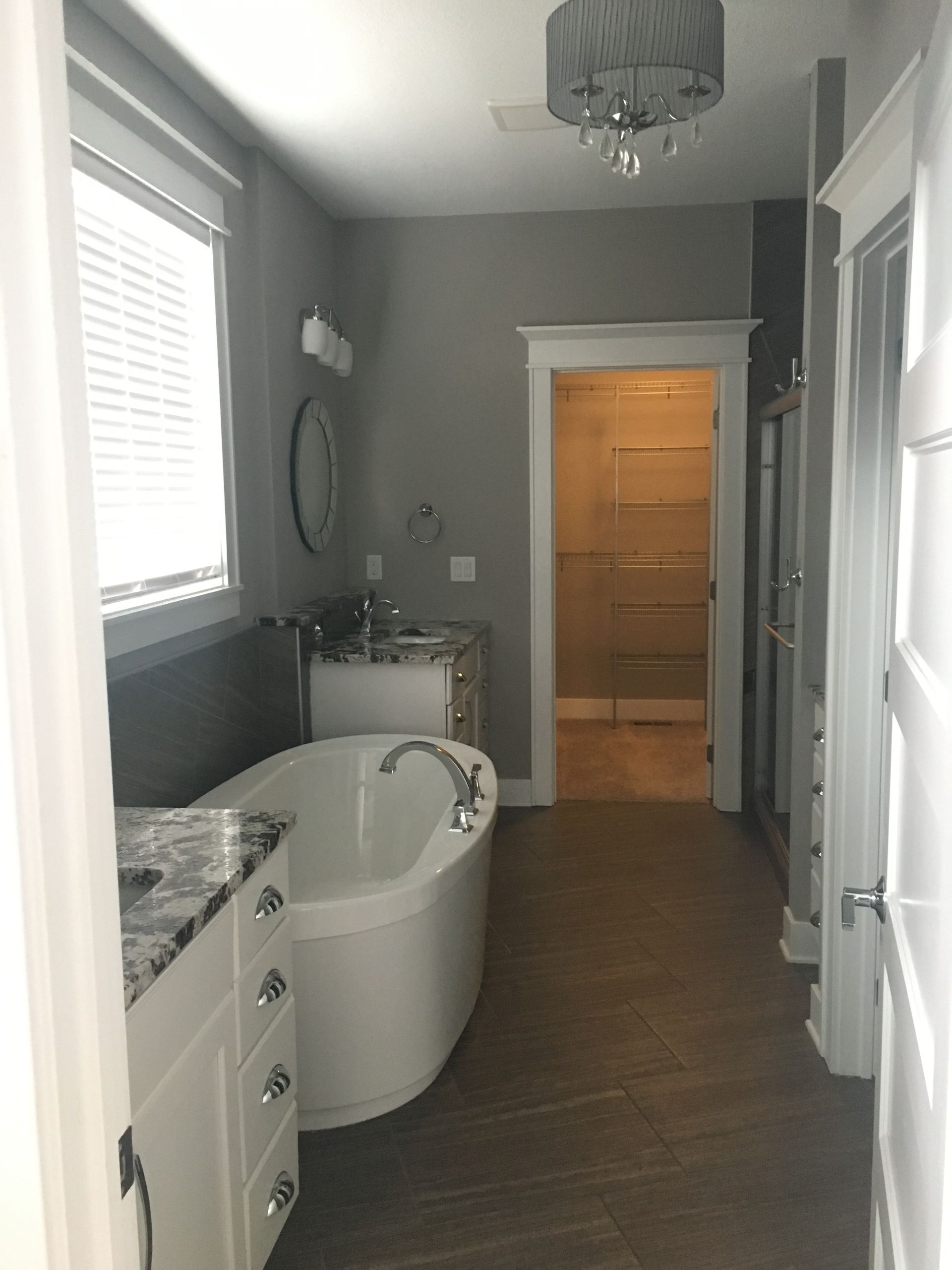 Modern bathroom with a freestanding tub, vanity, and glass shower, shown in gray and white tones.