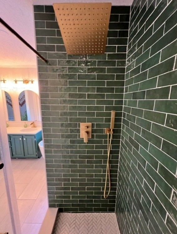 Green tiled shower with wood ceiling panel, wall-mounted controls, and a handheld showerhead.