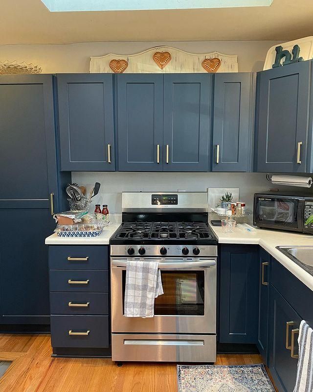 Modern kitchen with blue cabinets, stainless steel stove, white countertops, and decorative accents above cabinets
