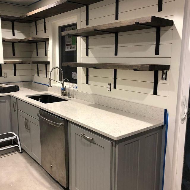 Modern kitchen with gray cabinets, white countertops, sink, dishwasher, and open wall shelves