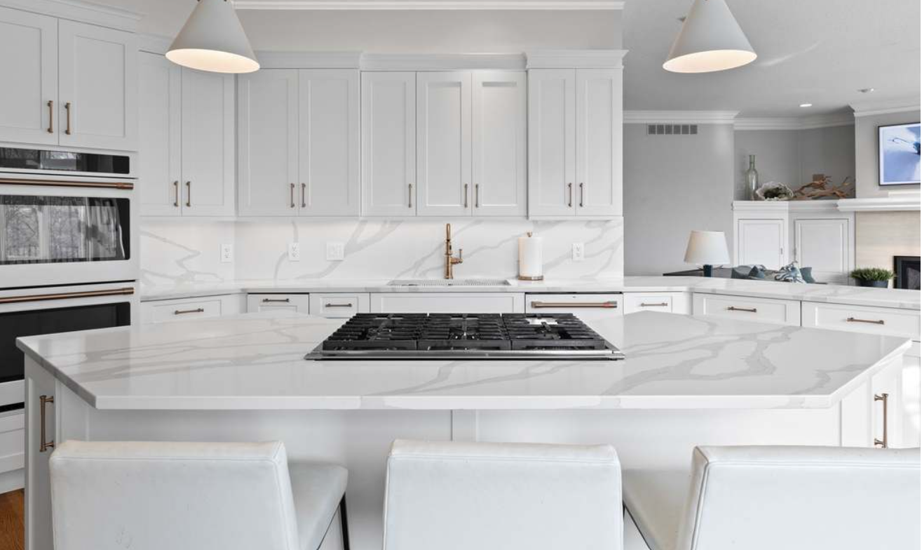 Bright modern white kitchen with marble island, pendant lights, and built-in appliances