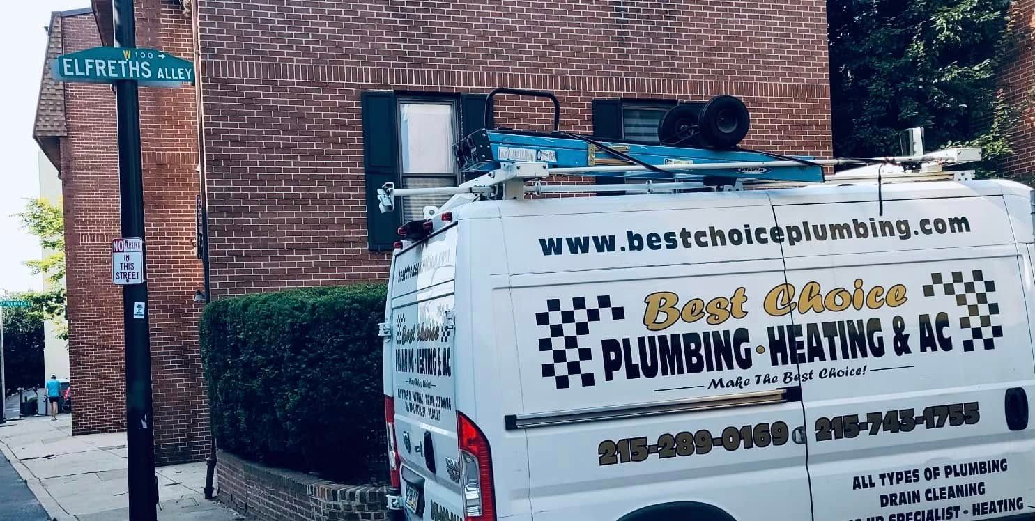 A plumbing van is parked in front of a brick building.