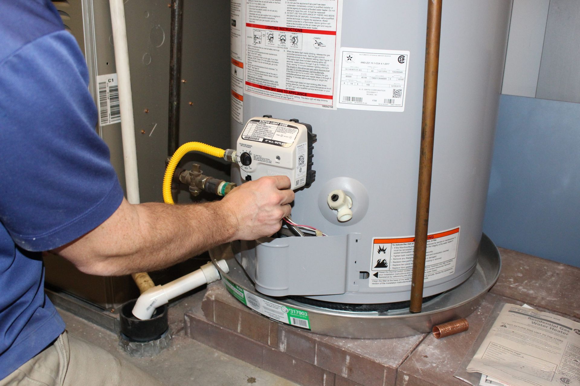 A man is working on a water heater in a basement.