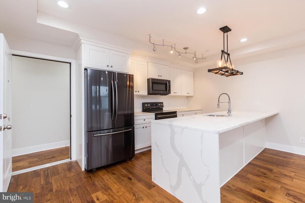 A kitchen with a large island, a refrigerator, a microwave, and a sink