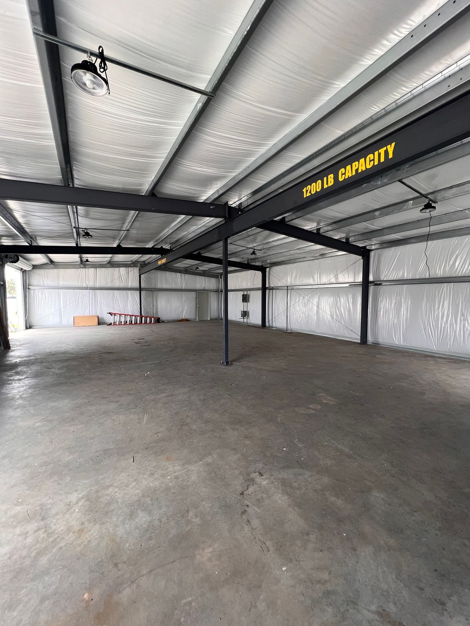 Empty industrial warehouse interior with concrete floor, metal beams, and insulated walls.