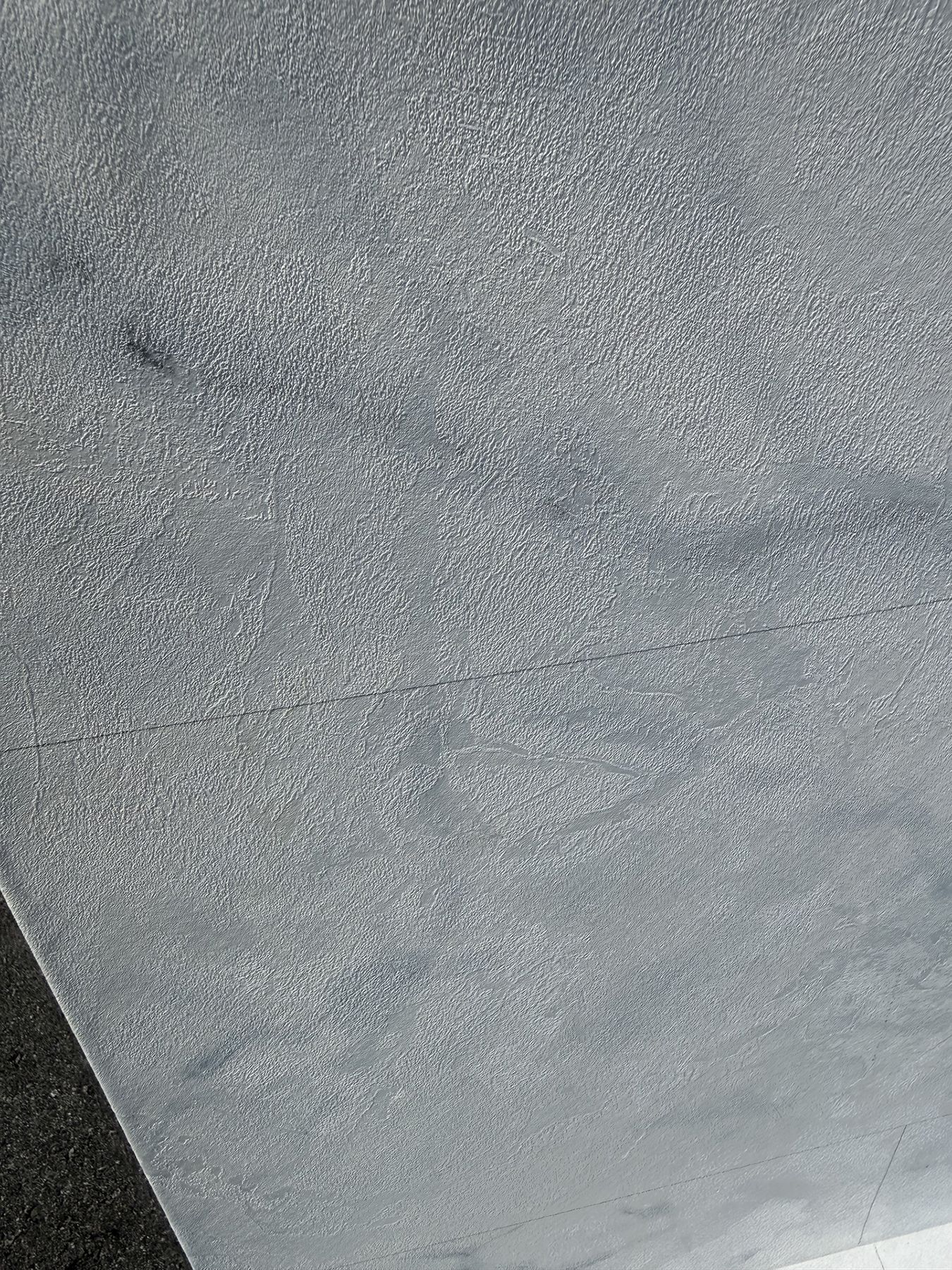 Close-up of a gray, textured surface with a dark diagonal edge in the corner