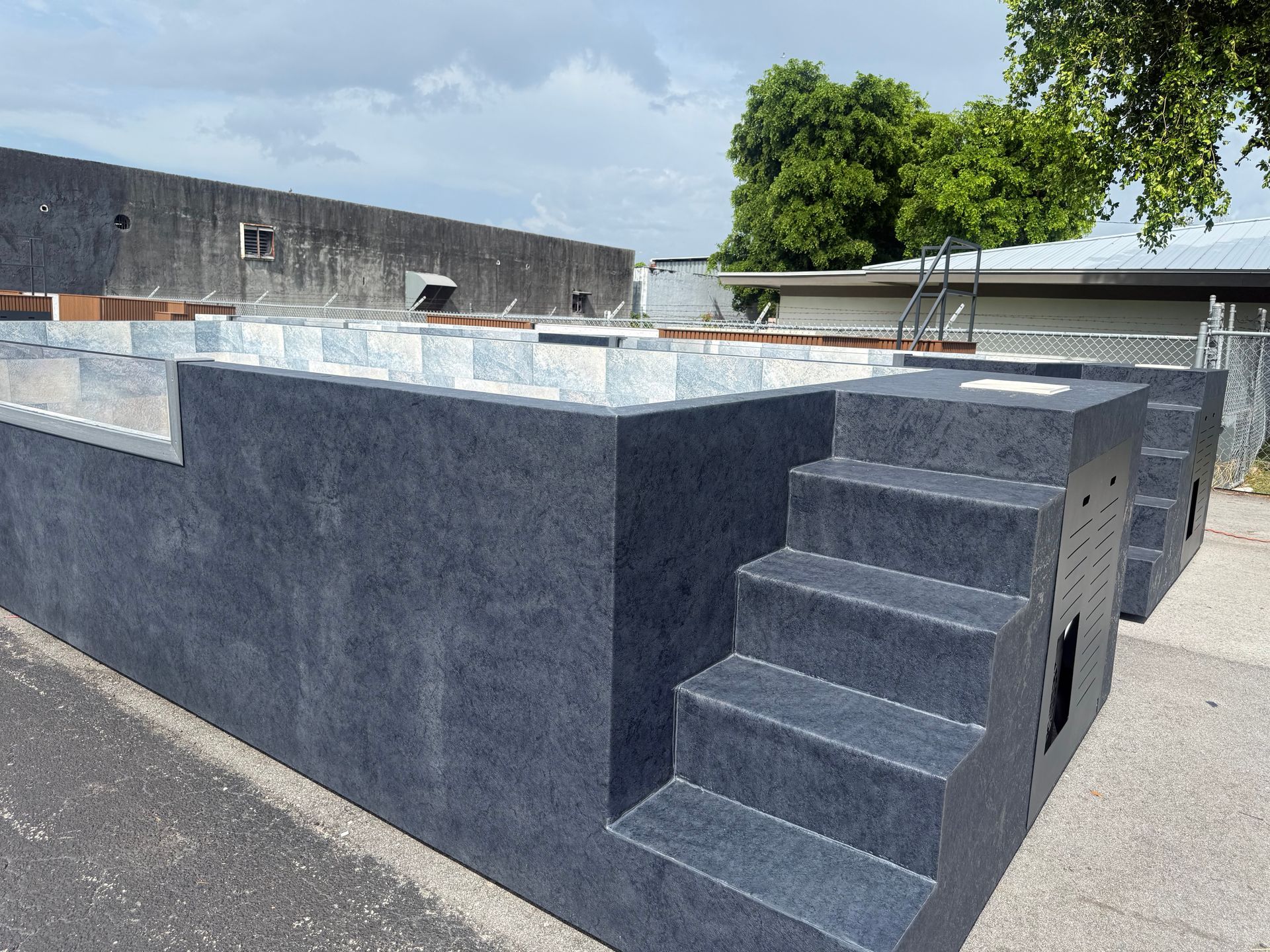 Gray outdoor concrete platform with steps on the right, in an industrial lot under a cloudy sky
