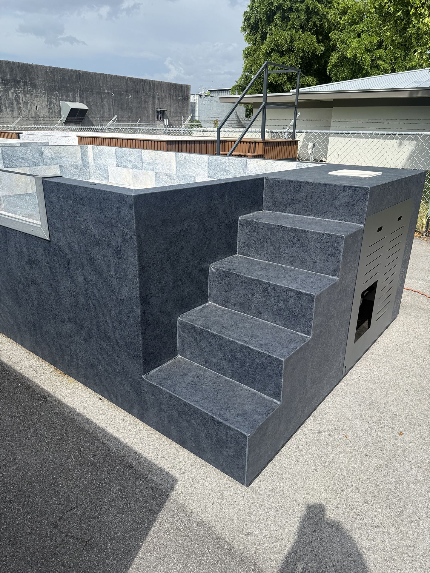 Outdoor concrete rooftop structure with dark gray steps and a white-and-gray wall on top