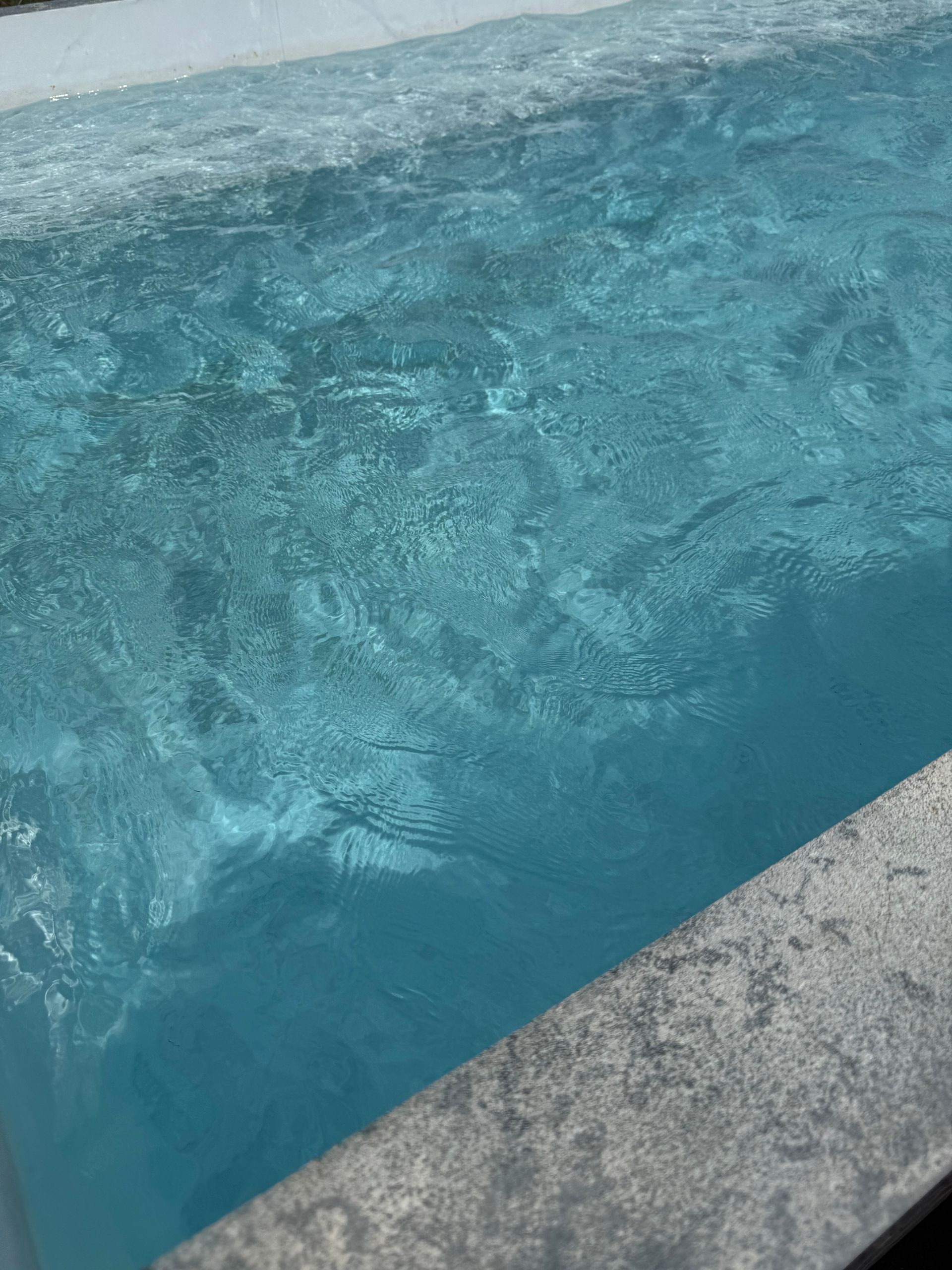 Blue water churning beside a concrete pool edge
