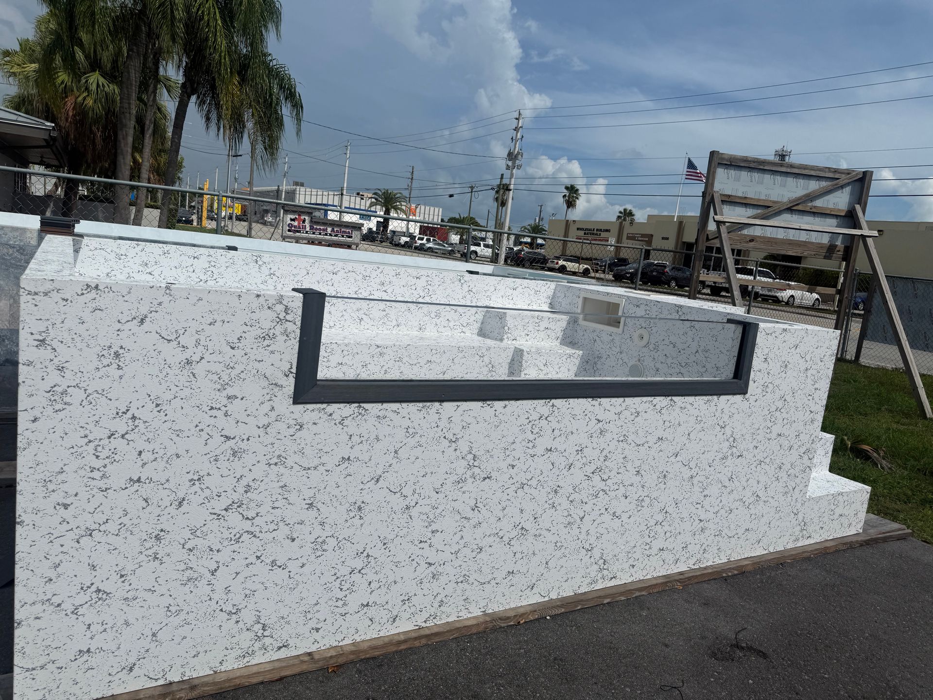 White speckled monument sign with a dark metal frame beside a road under cloudy skies