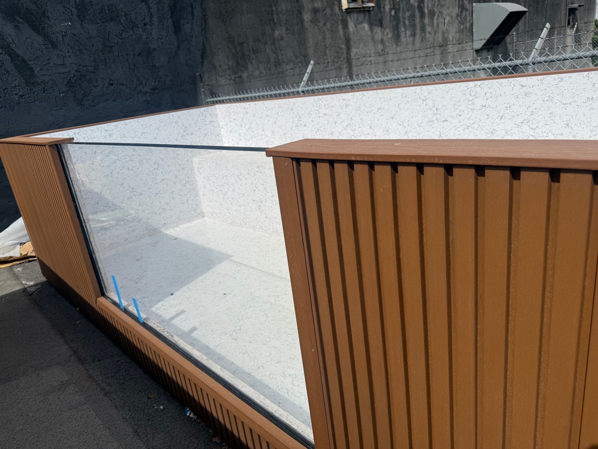 Modern balcony with frosted glass railing and brown slatted panels along a curved edge