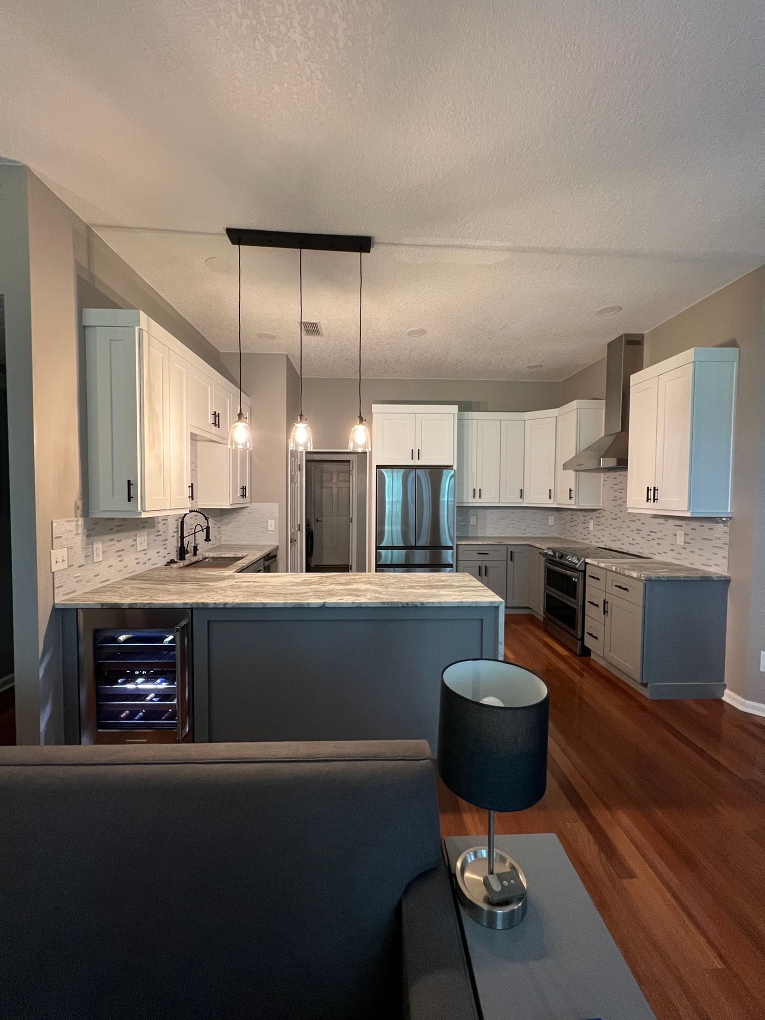 Modern kitchen with gray and white cabinets, stainless steel appliances, and a gray island.