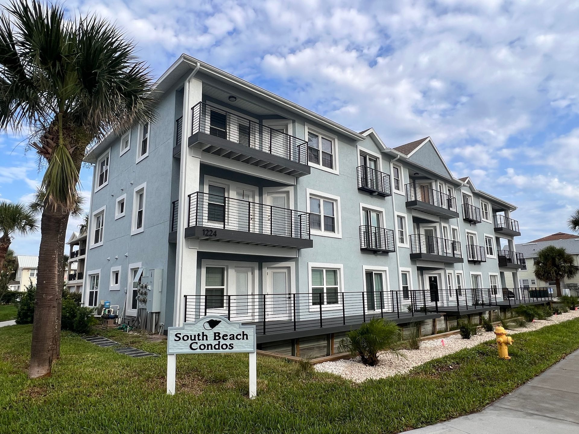 Three-story, light-blue condo building with balconies, 