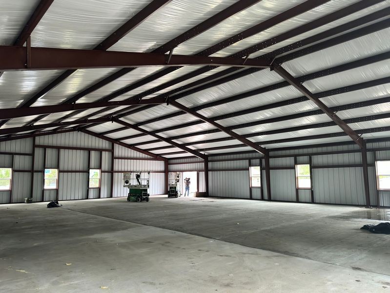 Steel-framed warehouse interior; empty space with concrete floor, metal walls, and insulated ceiling.